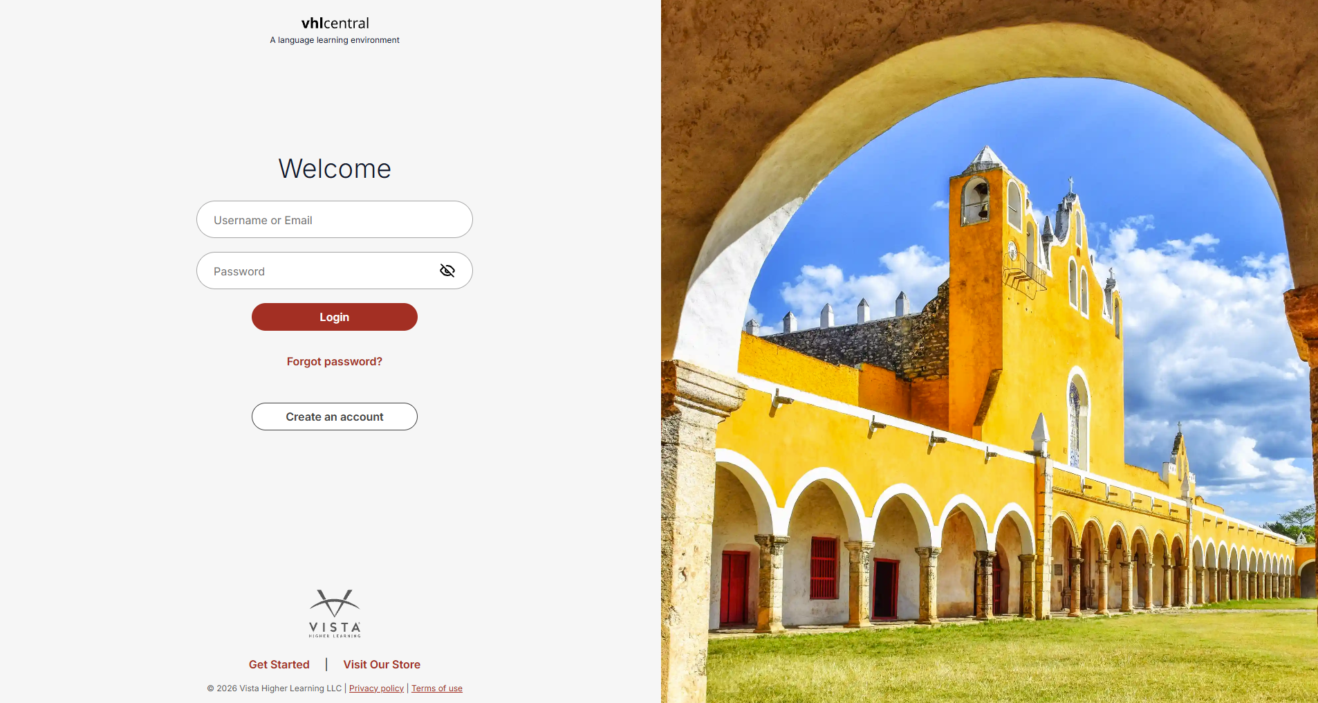 VHL Central login page with fields for Username or Email and Password, a Login button, Forgot password? link, and Create an account button. The left side displays the login form and Vista Higher Learning branding, while the right side features a large photograph of a yellow historic building with arches, a bell tower, and a grassy courtyard beneath a blue sky.